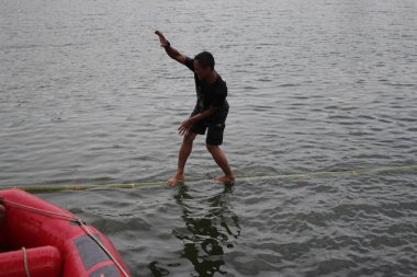 Sukabumi, Batı Java, Endonezya - 22 Ağustos 2021: Endonezyalı bir adam bambu üzerinde yürümeye çalışırken suya düşer ve Endonezya Bağımsızlık Günü boyunca Panjat Pinang adı verilen geleneksel oyunları oynamaya çalışır