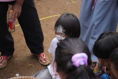 Sukabumi, Batı Java, Endonezya - 19 Ağustos 2021: Endonezyalı tatlı bir kızın yüzü, Endonezya 'nın bağımsızlık gününde Nyiru adlı bir yiyecek konteynerinden para almak için yarışırken buğday dolu.