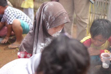 Sukabumi, Batı Java, Endonezya - 19 Ağustos 2021: Endonezyalı tatlı bir kızın yüzü, Endonezya 'nın bağımsızlık gününde Nyiru adlı bir yiyecek konteynerinden para almak için yarışırken buğday dolu.