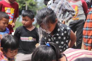 Sukabumi, Batı Java, Endonezya - 19 Ağustos 2021: Endonezyalı tatlı bir kızın yüzü, Endonezya 'nın bağımsızlık gününde Nyiru adlı bir yiyecek konteynerinden para almak için yarışırken buğday dolu.