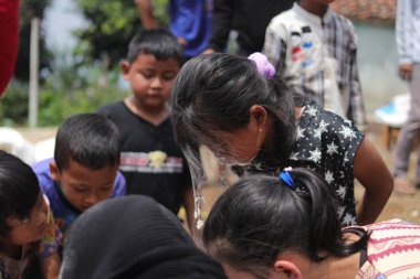 Sukabumi, Batı Java, Endonezya - 19 Ağustos 2021: Endonezyalı tatlı bir kızın yüzü, Endonezya 'nın bağımsızlık gününde Nyiru adlı bir yiyecek konteynerinden para almak için yarışırken buğday dolu.