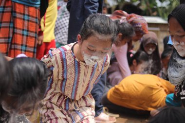 Sukabumi, Batı Java, Endonezya - 19 Ağustos 2021: Endonezyalı tatlı bir kızın yüzü, Endonezya 'nın bağımsızlık gününde Nyiru adlı bir yiyecek konteynerinden para almak için yarışırken buğday dolu.