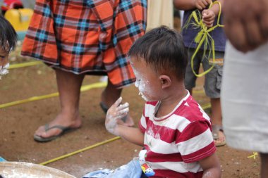 Sukabumi, Batı Java, Endonezya - 19 Ağustos 2021: Endonezya 'nın bağımsızlık gününde Endonezya' nın Nyiru adlı yiyecek konteynırından para almak için yarışırken tatlı bir Endonezyalı çocuğun yüzü buğday dolu.