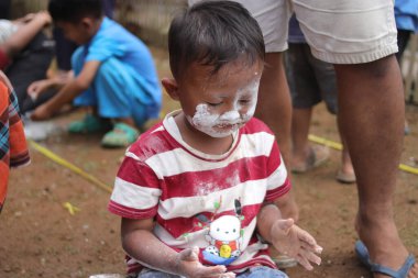 Sukabumi, Batı Java, Endonezya - 19 Ağustos 2021: Endonezya 'nın bağımsızlık gününde Endonezya' nın Nyiru adlı yiyecek konteynırından para almak için yarışırken tatlı bir Endonezyalı çocuğun yüzü buğday dolu.