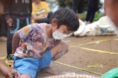 Sukabumi, Batı Java, Endonezya - 19 Ağustos 2021: Endonezya 'nın bağımsızlık gününde Endonezya' nın Nyiru adlı yiyecek konteynırından para almak için yarışırken tatlı bir Endonezyalı çocuğun yüzü buğday dolu.
