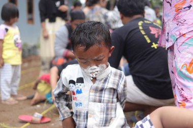 Sukabumi, Batı Java, Endonezya - 19 Ağustos 2021: Endonezya 'nın bağımsızlık gününde Endonezya' nın Nyiru adlı yiyecek konteynırından para almak için yarışırken tatlı bir Endonezyalı çocuğun yüzü buğday dolu.