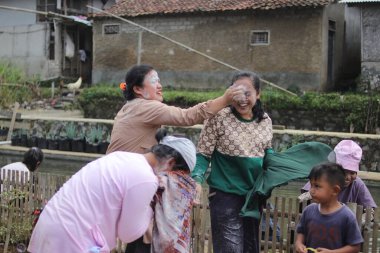 Sukabumi, Batı Java, Endonezya - 19 Ağustos 2021: Endonezyalı kadınlar, Endonezya bağımsızlık günü boyunca buğday dolu Nyiru adlı bir yiyecek konteynerinden para almak için yarıştıktan sonra eğleniyorlar.