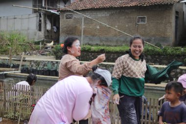 Sukabumi, Batı Java, Endonezya - 19 Ağustos 2021: Endonezyalı kadınlar, Endonezya bağımsızlık günü boyunca buğday dolu Nyiru adlı bir yiyecek konteynerinden para almak için yarıştıktan sonra eğleniyorlar.