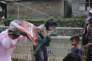 Sukabumi, Batı Java, Endonezya - 19 Ağustos 2021: Endonezyalı kadınlar, Endonezya bağımsızlık günü boyunca buğday dolu Nyiru adlı bir yiyecek konteynerinden para almak için yarıştıktan sonra eğleniyorlar.