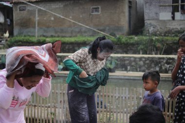 Sukabumi, Batı Java, Endonezya - 19 Ağustos 2021: Endonezyalı kadınlar, Endonezya bağımsızlık günü boyunca buğday dolu Nyiru adlı bir yiyecek konteynerinden para almak için yarıştıktan sonra eğleniyorlar.