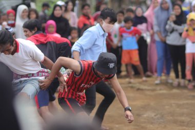 Sukabumi, Batı Java, Endonezya - 22 Ağustos 2021: Sarong kullanarak bağlanmış bir grup Endonezyalı, Endonezya Bağımsızlık Günü sırasında Tarık Sarong veya Tarık sarung adı verilen geleneksel bir oyunda birbirini çekiyor