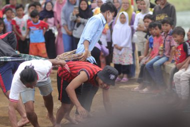 Sukabumi, Batı Java, Endonezya - 22 Ağustos 2021: Sarong kullanarak bağlanmış bir grup Endonezyalı, Endonezya Bağımsızlık Günü sırasında Tarık Sarong veya Tarık sarung adı verilen geleneksel bir oyunda birbirini çekiyor