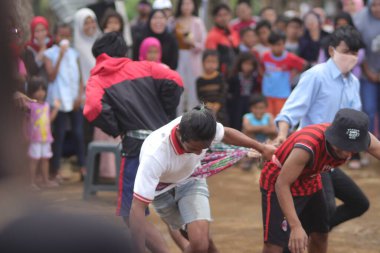 Sukabumi, Batı Java, Endonezya - 22 Ağustos 2021: Sarong kullanarak bağlanmış bir grup Endonezyalı, Endonezya Bağımsızlık Günü sırasında Tarık Sarong veya Tarık sarung adı verilen geleneksel bir oyunda birbirini çekiyor