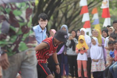 Sukabumi, Batı Java, Endonezya - 22 Ağustos 2021: Sarong kullanarak bağlanmış bir grup Endonezyalı, Endonezya Bağımsızlık Günü sırasında Tarık Sarong veya Tarık sarung adı verilen geleneksel bir oyunda birbirini çekiyor