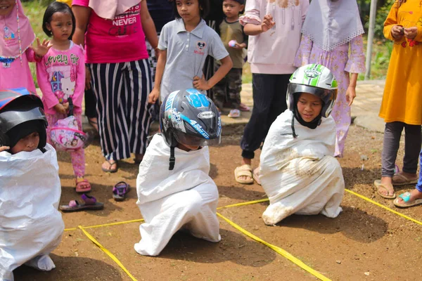 Sukabumi, Batı Java, Endonezya - 19 Ağustos 2021: Endonezyalı miğferli bir grup çocuk Endonezya 'nın Bağımsızlık Günü' nde Balap Karung veya Sack Race adlı geleneksel oyunlarıyla mücadele ediyor