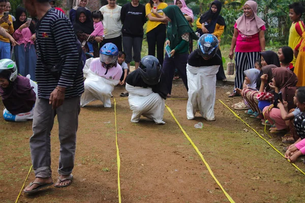 Sukabumi, Batı Java, Endonezya - 19 Ağustos 2021: Endonezyalı miğferli bir grup kadın Endonezya Bağımsızlık Günü 'nde Balap Karung veya Sack Race adlı geleneksel Endonezya oyunlarıdır.