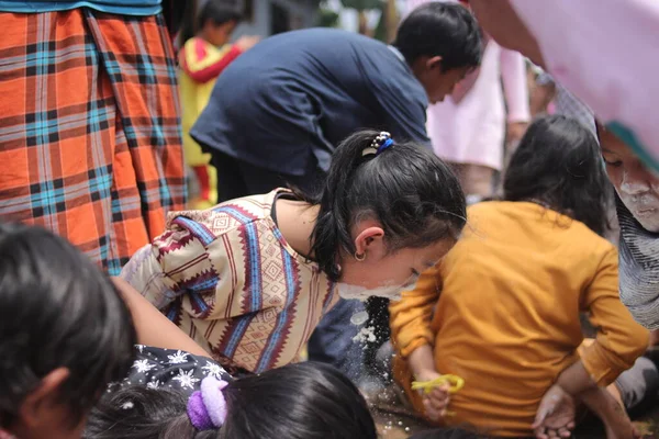 Sukabumi, Batı Java, Endonezya - 19 Ağustos 2021: Endonezyalı tatlı bir kızın yüzü, Endonezya 'nın bağımsızlık gününde Nyiru adlı bir yiyecek konteynerinden para almak için yarışırken buğday dolu.