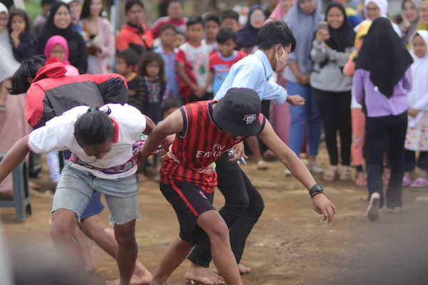 Sukabumi, Batı Java, Endonezya - 22 Ağustos 2021: Sarong kullanarak bağlanmış bir grup Endonezyalı, Endonezya Bağımsızlık Günü sırasında Tarık Sarong veya Tarık sarung adı verilen geleneksel bir oyunda birbirini çekiyor