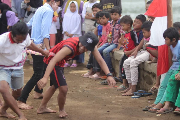 Sukabumi, Batı Java, Endonezya - 22 Ağustos 2021: Sarong kullanarak bağlanmış bir grup Endonezyalı, Endonezya Bağımsızlık Günü sırasında Tarık Sarong veya Tarık sarung adı verilen geleneksel bir oyunda birbirini çekiyor