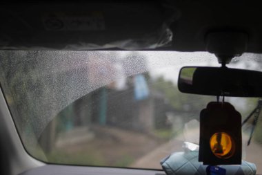 Yağmurlu bir günde arabanın ön camına yağmur damlaları damlıyor..