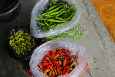Endonezyalı yerel çiftçiler tarlalardan toplanan beyaz plastik poşetlerde çeşitli kırmızı biberler satmaya hazır.