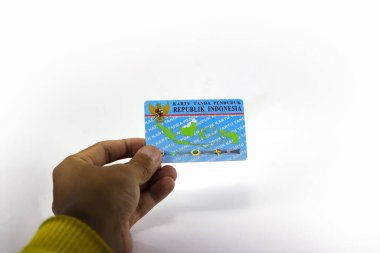 Sukabumi, Batı Java, Endonezya - 14 Ekim 2021: Asyalı bir adamın sol eli, E-KTP adında bir Endonezya Elektronik Kimlik Kartı tutuyor..