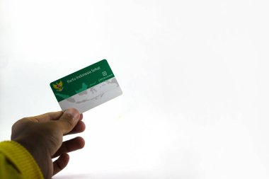 Sukabumi, Batı Java, Endonezya - 14 Ekim 2021: Endonezya Hükümeti 'nden Kartu Endonezya Sehat' ın (KIS veya Sağlık Sigorta Kartı) beyaz arka planda izole edilmiş bir Asyalı adamın elini tutuyor.