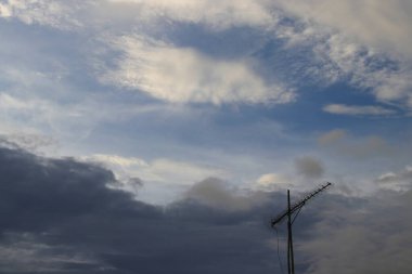 Koyu gri bulutlar ve turuncu gölgelerle güzel, dramatik bir akşam göğü.