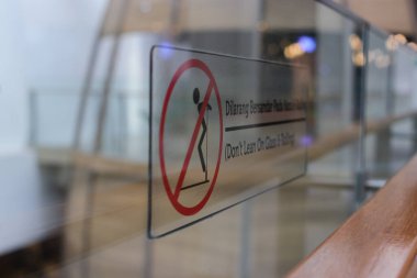 Endonezya 'da bir alışveriş merkezinde cam bariyerlere yaslanmayın (Dilarang Bersandar) seçici odak noktası.