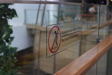 Endonezya 'da bir alışveriş merkezinde cam bariyerlere yaslanmayın (Dilarang Bersandar) seçici odak noktası.