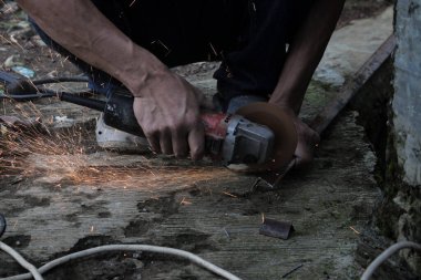 Bir adam bir metali elektrikli kaynak makinesi ile kaynak yapar, kaynakçı, kaynak metali, adam metalle çalışır.