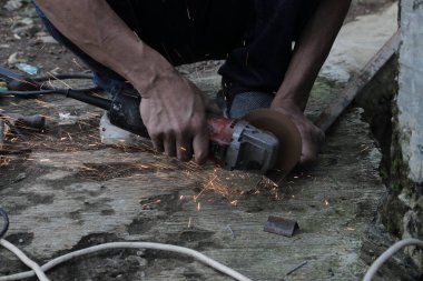 Bir adam bir metali elektrikli kaynak makinesi ile kaynak yapar, kaynakçı, kaynak metali, adam metalle çalışır.