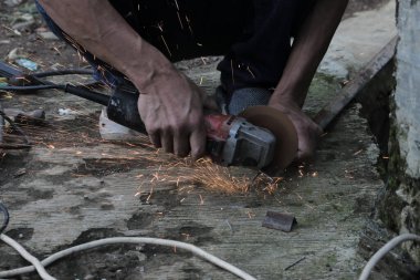 Bir adam bir metali elektrikli kaynak makinesi ile kaynak yapar, kaynakçı, kaynak metali, adam metalle çalışır.