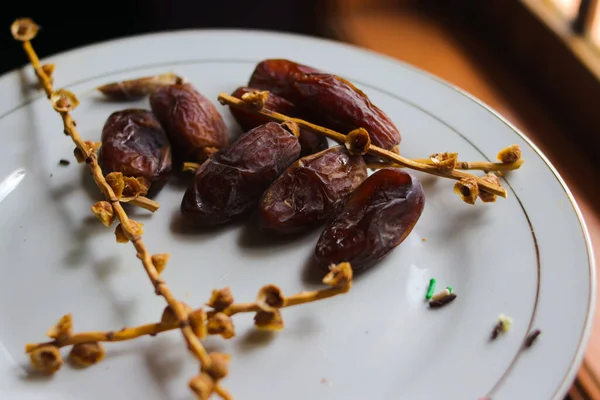 Close-up view of ripe date palm fruit on white plate is ready to eat. Date palm fruit is one of popular dried fruits in Islam especially during Ramadan.