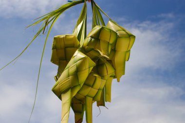 Bir grup boş ketupat derisi ya da ketupat kesesi piyasada asılı ve satılıyor. Genellikle Hari Raya ya da bayram mübarek zamanında servis edilen ketupat kesesi örülmüş genç hindistan cevizi yapraklarından yapılır.