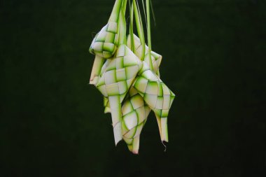Bir grup boş ketupat derisi ya da ketupat kesesi. Telif alanı ve yeşil arkaplan. Ketupat genellikle Hari Raya ya da bayram zamanında servis edilir. Ketupat kesesi örülmüş genç hindistan cevizi yapraklarından yapılır.