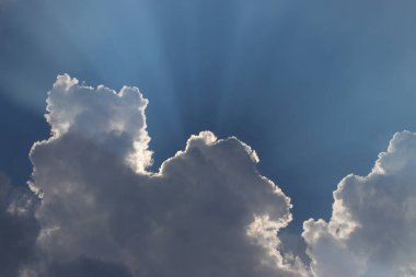 Bulutların arkasında güneş ışınları ve kopyalama alanı olan mavi gökyüzü arkaplanı.