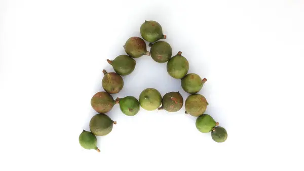 Sekelompok Kacang Macadamia Mentah Pada Huruf Yang Dibentuk Dengan Ruang — Stok Foto
