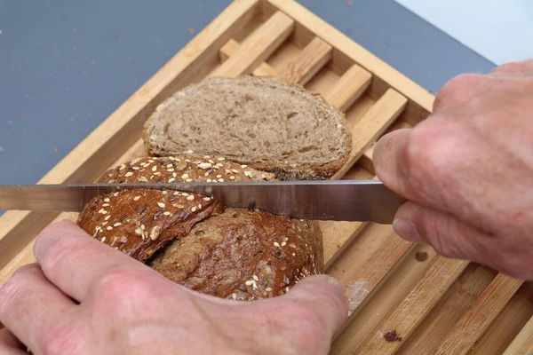 man\'s hands cutting thick slices of bread