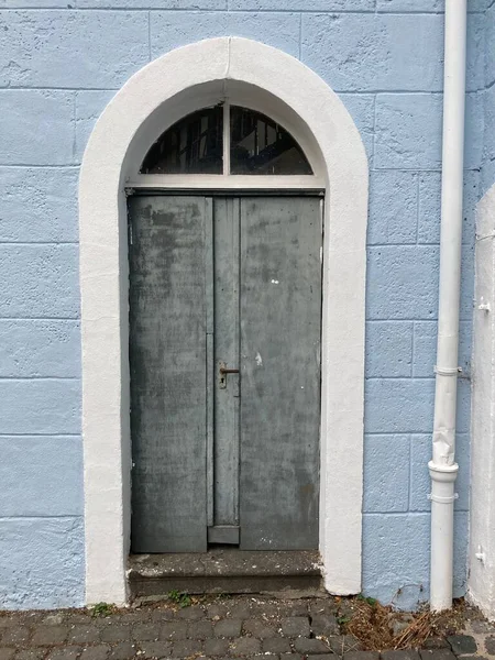 Stare Szare Drzwi Białą Łukową Ramą Ceglanej Ścianie Malowane Niebiesko — Zdjęcie stockowe
