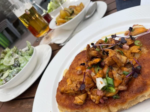 Kızarmış patatesle servis edilen mantarlı bavyera yemeği ve ayrı kaselerde yeşil salata.