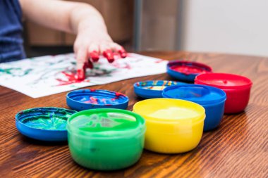 Mutlu çocuk elleri boyalı resim çizer.