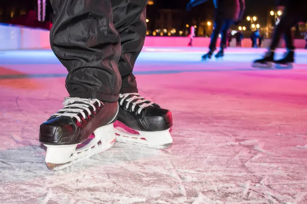 black ice skates in ice rink with staitings people background