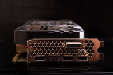 the video card lies with its end with video ports on a black background, soft focus