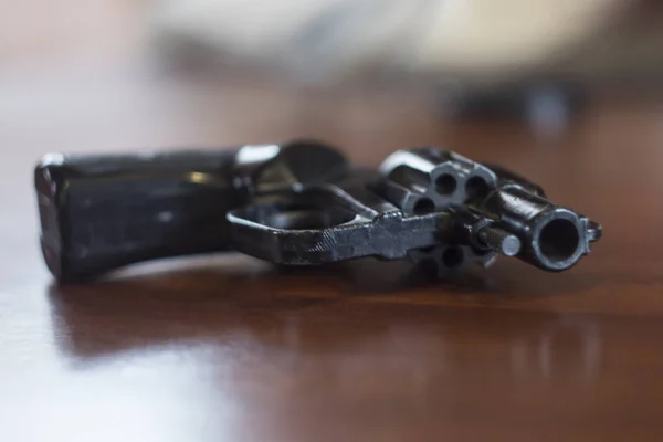 siyah bir revolver kahverengi masanın üzerinde yatıyor.
