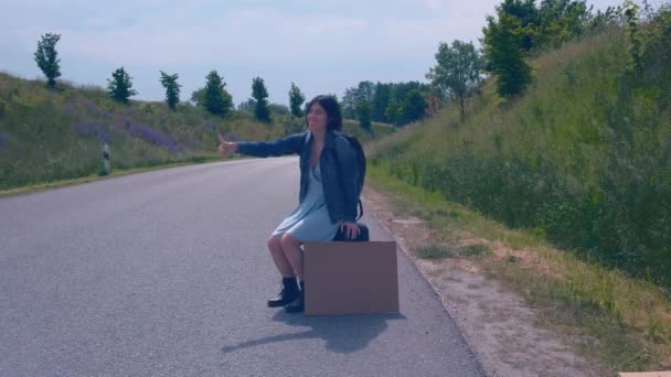 旅行やヒッチハイクのコンセプト。道路で車を止めてハイキングする少女. — ストック動画