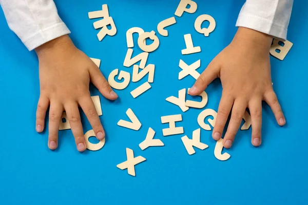The child lays out the letters on the table. The concept of the school of education. Soon to school