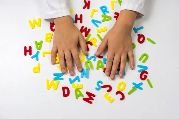 Colorful letters. The childs hands lay out colored letters on the table. Soon to school. School learning concept