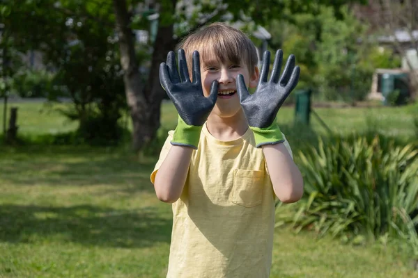 Boy in home garden wearing gardening gloves. gardening season