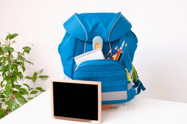 Soon to school. School backpack with writing supplies on the table